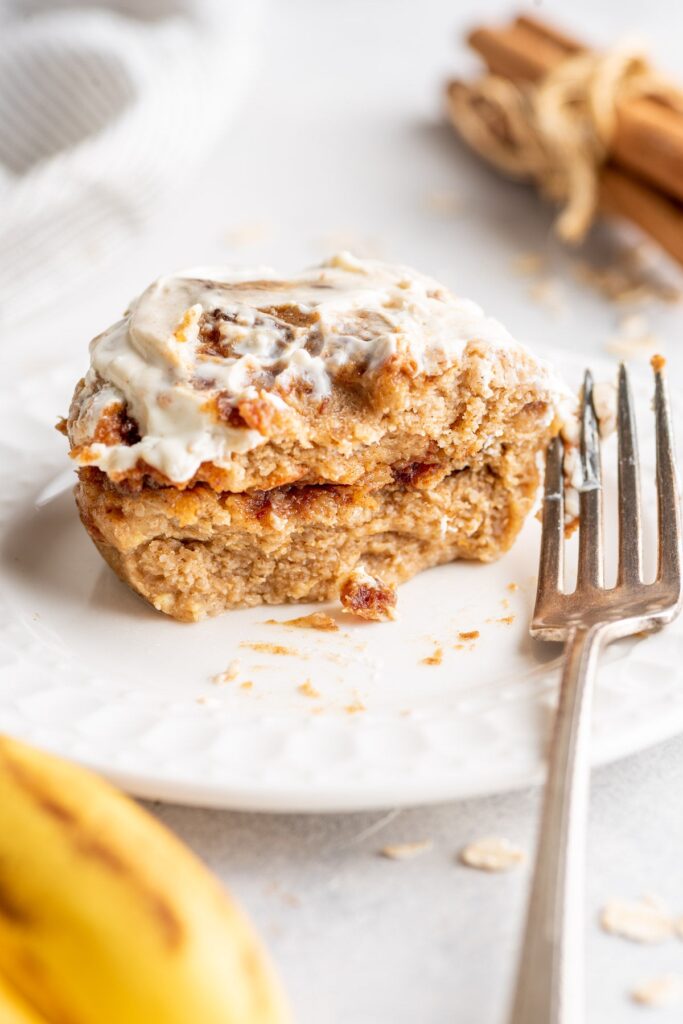 Half-eaten cinnamon roll on the plate with fork on the table
