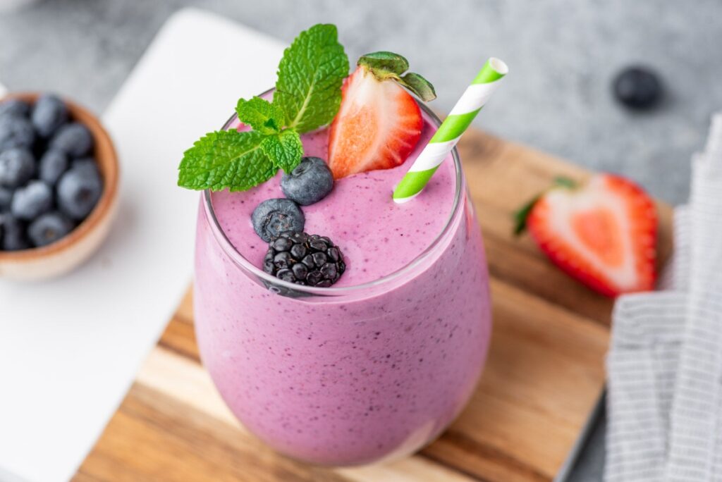 Berry smoothie that blasts belly fat in glass decorated with a straw, berries and mint
