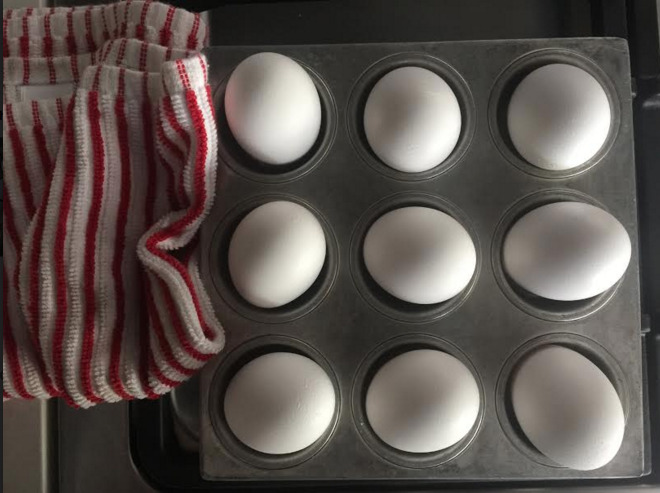 eggs in a muffin tin with a red and white striped towel