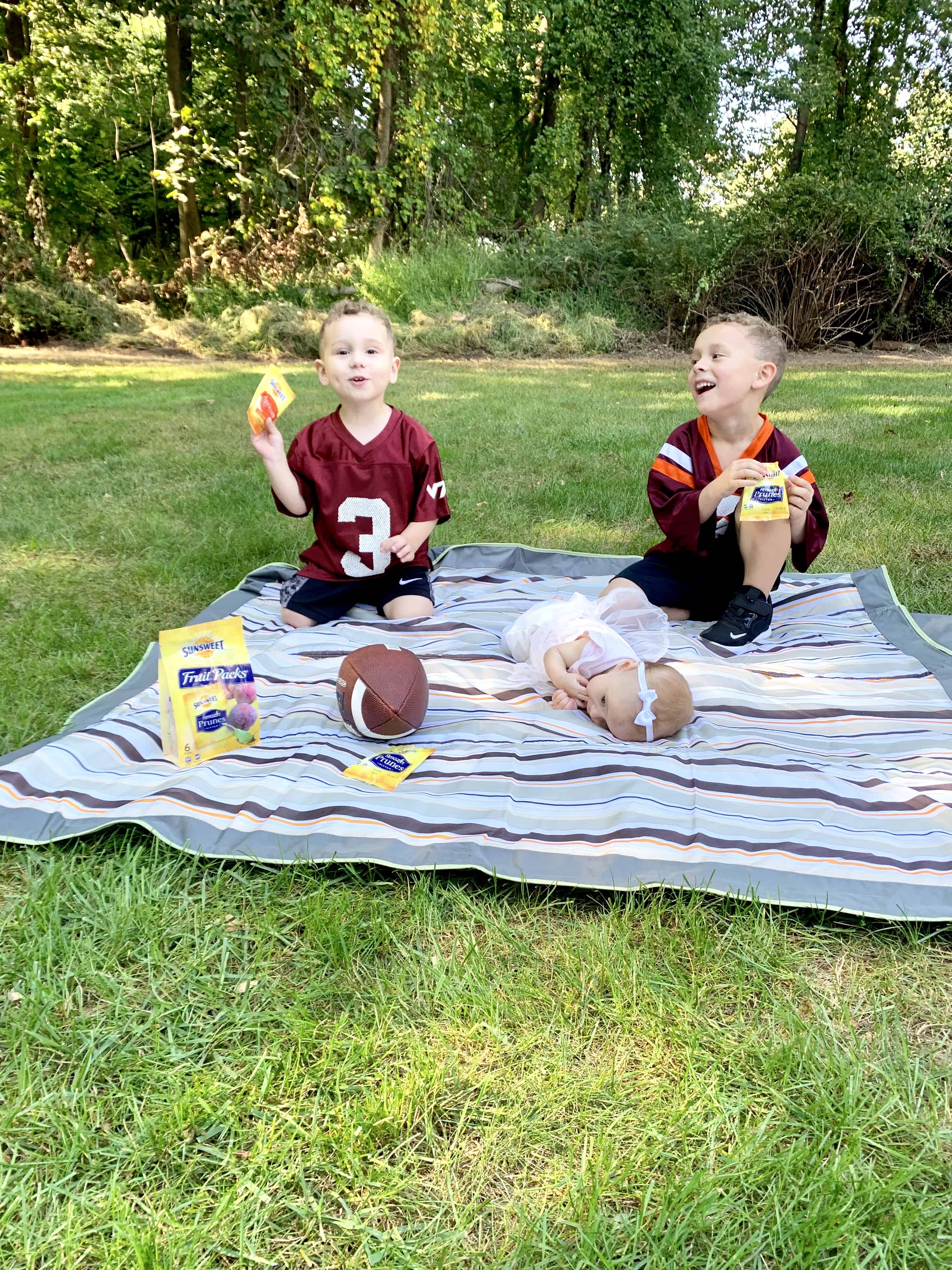 children eating a healthy afterschool snack on lawn playing football