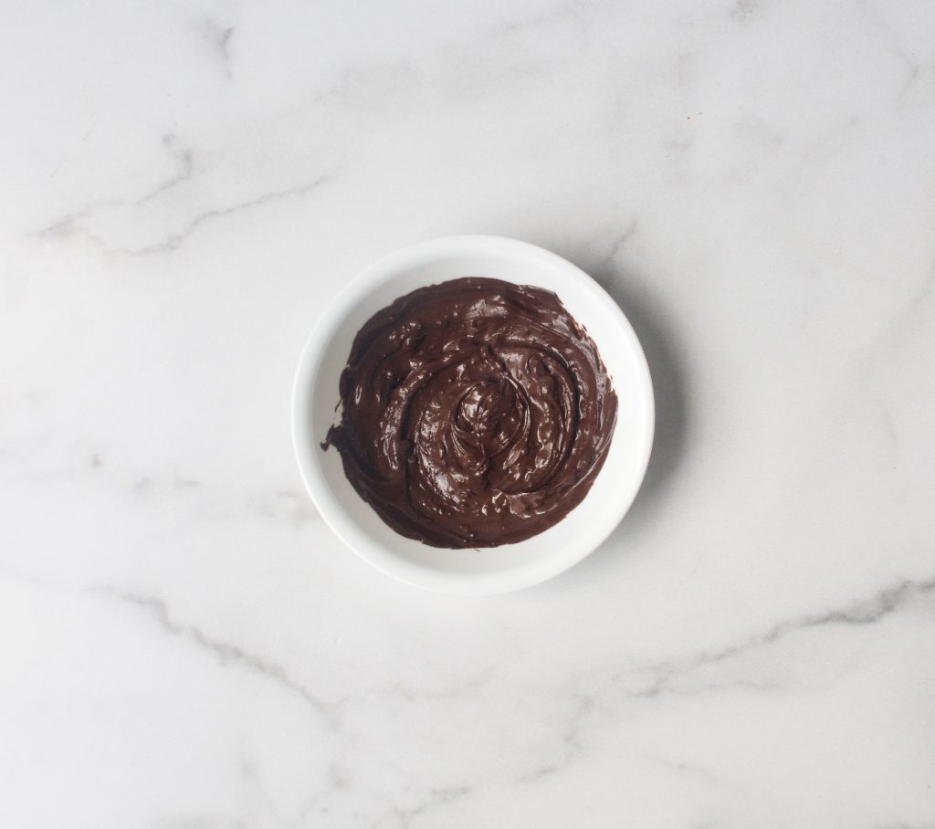 melted chocolate in a white bowl on a marble surface