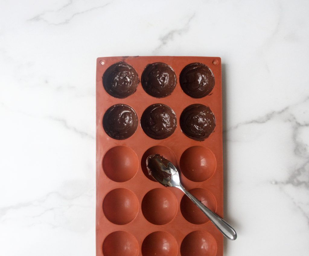 red silicone round chocolate mold with 6 molds filled with chocolate on a marble background