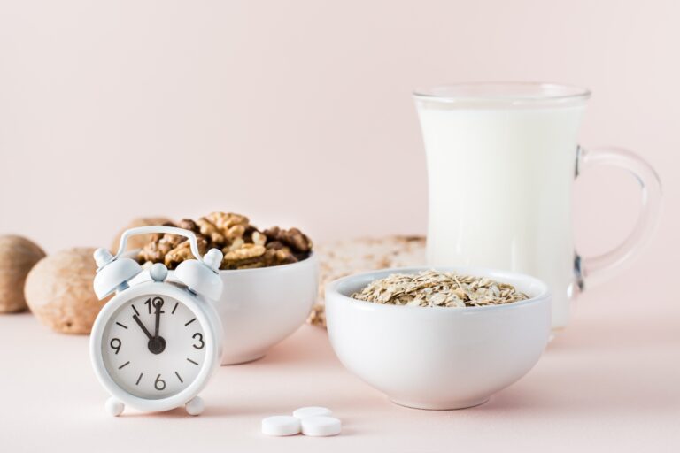 Clock with ball of oatmeal, ball of walnuts, pills and a jug of yogurt
