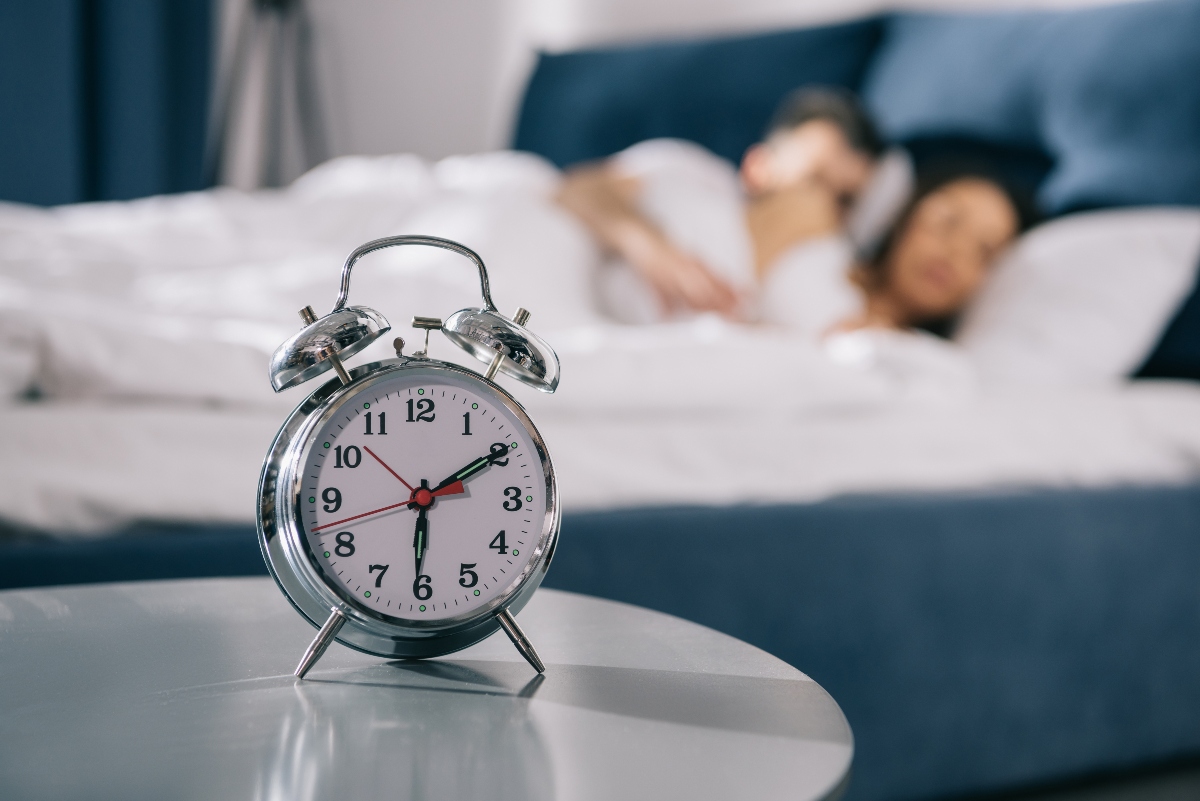 couple sleeping peacefully in bed with alarm clock 