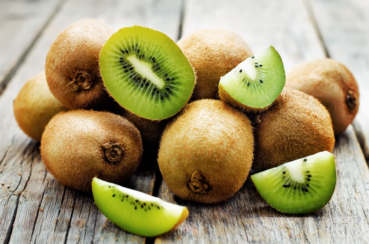 kiwifruit stacked together with some whole kiwi and some sliced