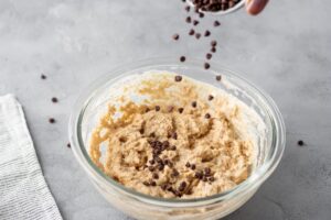 Making dough for pancakes in bowl and adding chocolate nibs to dough