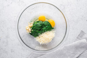 spinach eggs garlic and parmesan cheese in a glass bowl