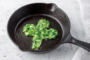 shamrock shaped green pancake in a cast iron skillet