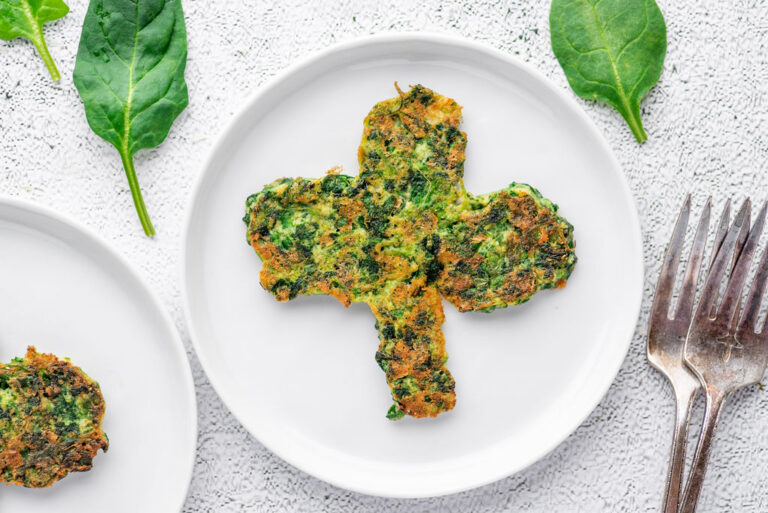 spinach pancake in the shape of a clover on a white plate with fork