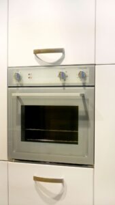 Oven build into white wood cabinet