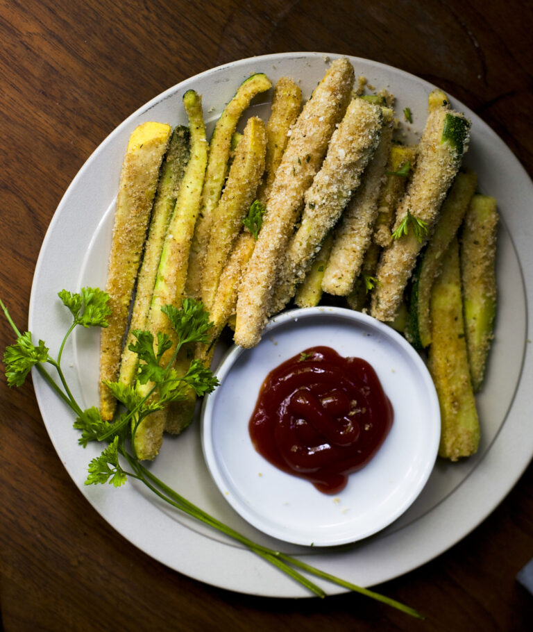 white plate of zucchini fries with a bowl of ketchup