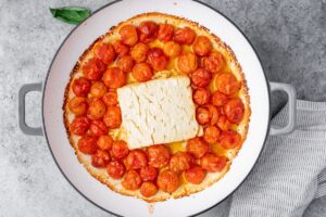 Baked feta, cherry tomatoes and olive oil in cooking pan