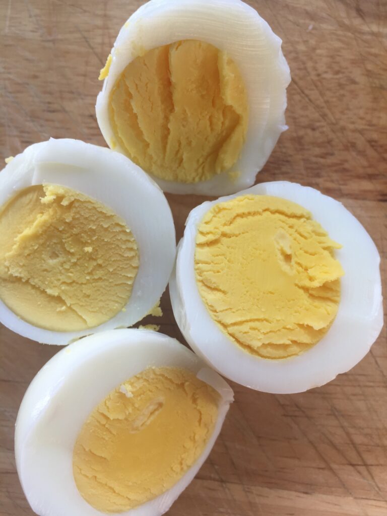 4 halves of hard boiled eggs on a wooden surface