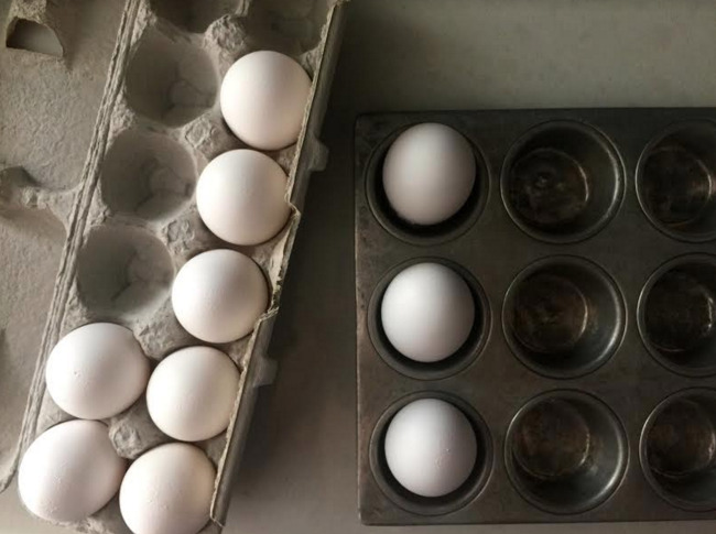 carton of eggs and a muffin tin with 3 eggs in the muffin spaces