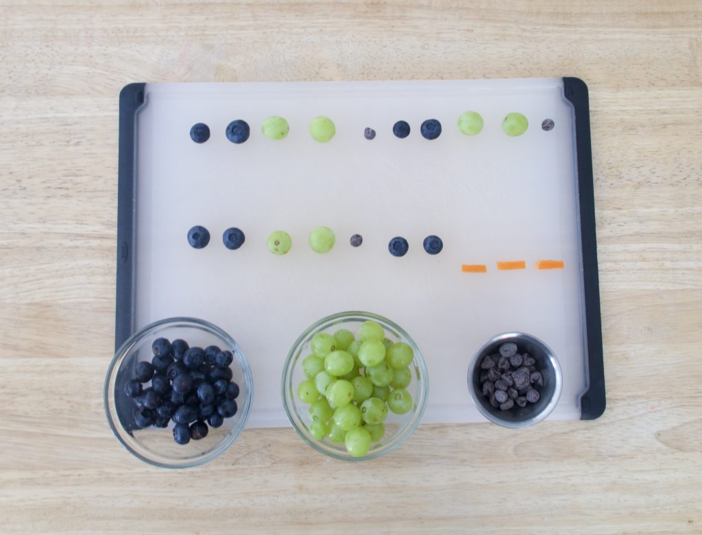 green grapes and blueberries on cutting board following a pattern
