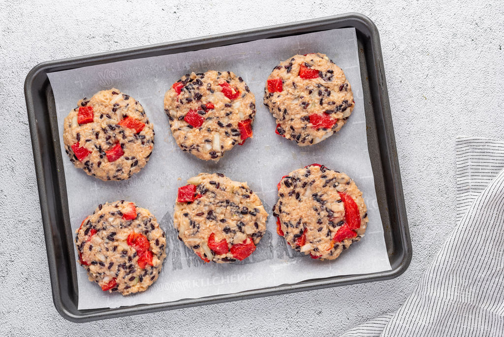 6 raw veggie burger patties on parchment paper on a baking sheet