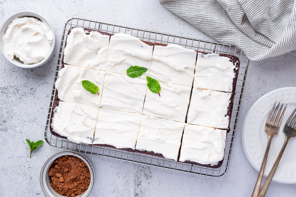 Keto chocolate cake with cup of cocoa powder, forks and cream beside