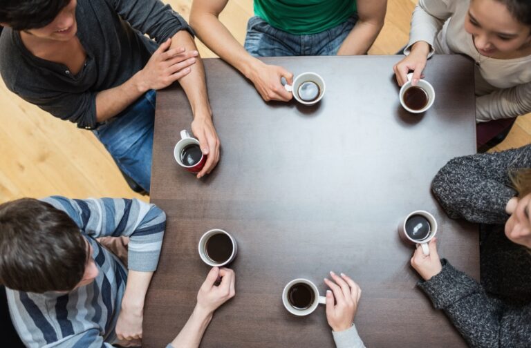 People sitting around table drinking coffee in cafe