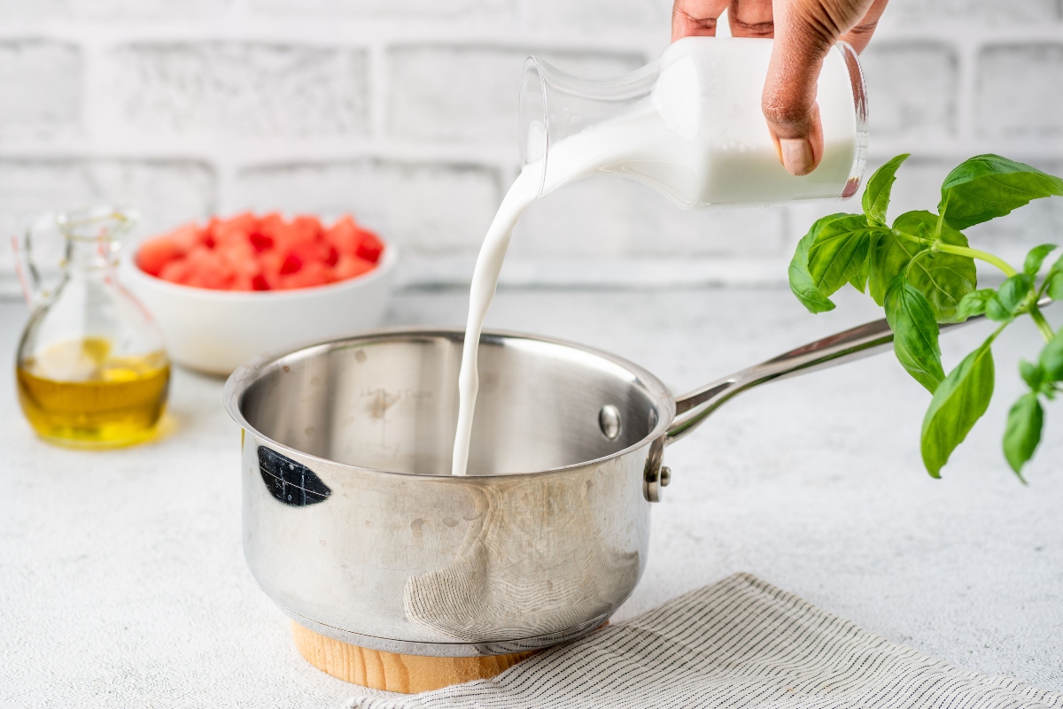 Pouring coconut milk in sauce pan to prepare watermelon salad with coconut rice