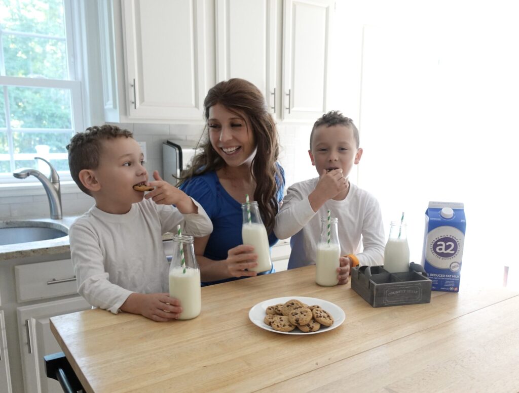 mother and sons enjoying a glass of milk and cookies while laughing