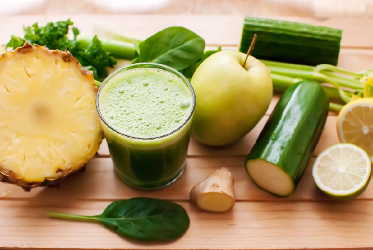 Celery juice in a glass with fruits and veggies around it