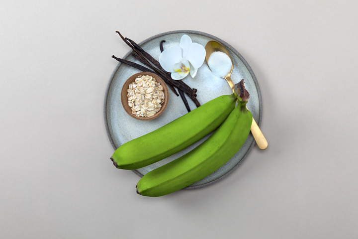 white plate with orchid, green bananas, and rolled oats