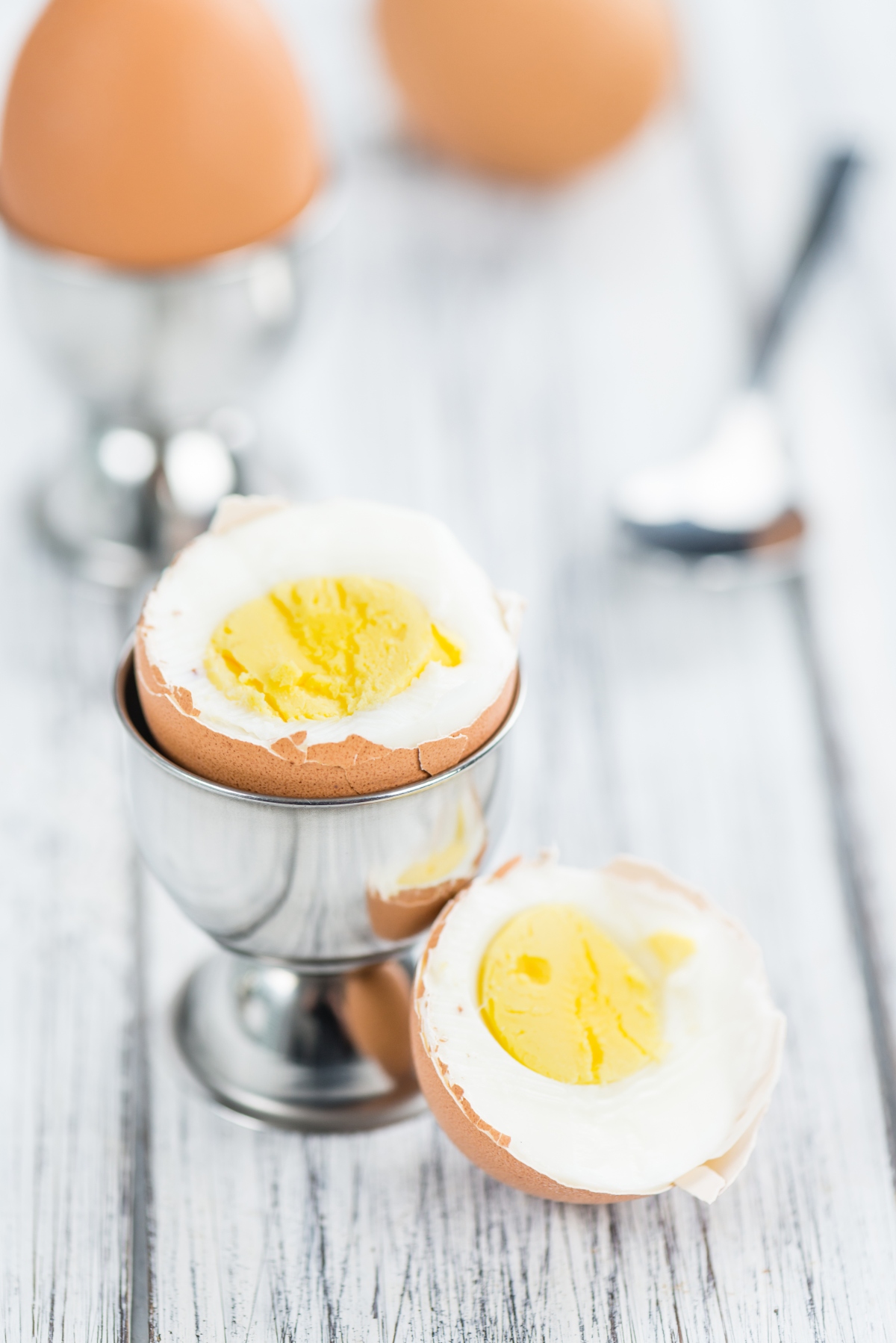 Boiled egg with eggshell in egg cup cut in half
