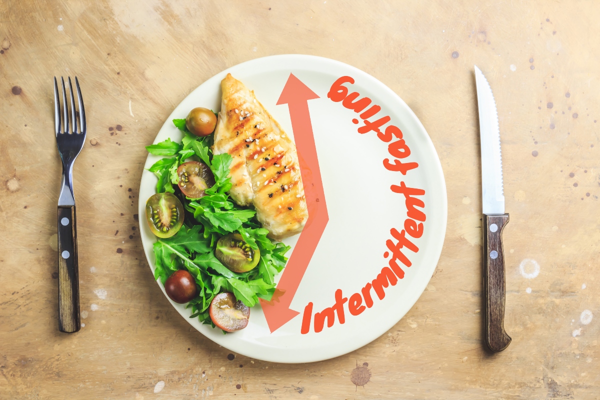 A plate with healthy food on one side and written "Intermittent fasting" on the other side