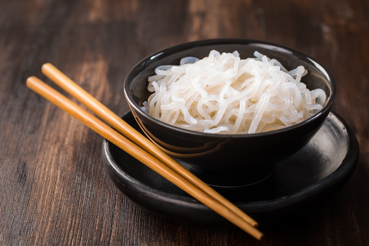 Shirataki noodles in black bowl with wooden chopsticks beside