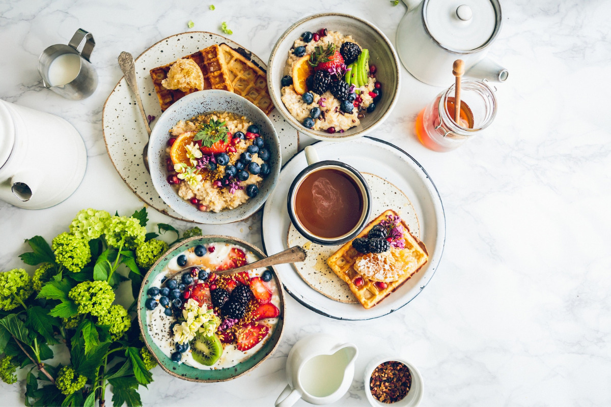 Various healthy foods on a table, waffle with fruit, salad, oatmeal and honey