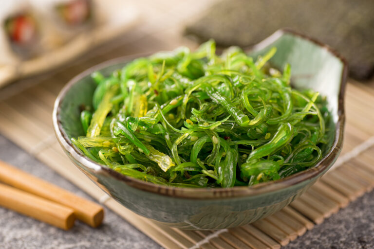 Seaweed salad in a bowl with sticks beside