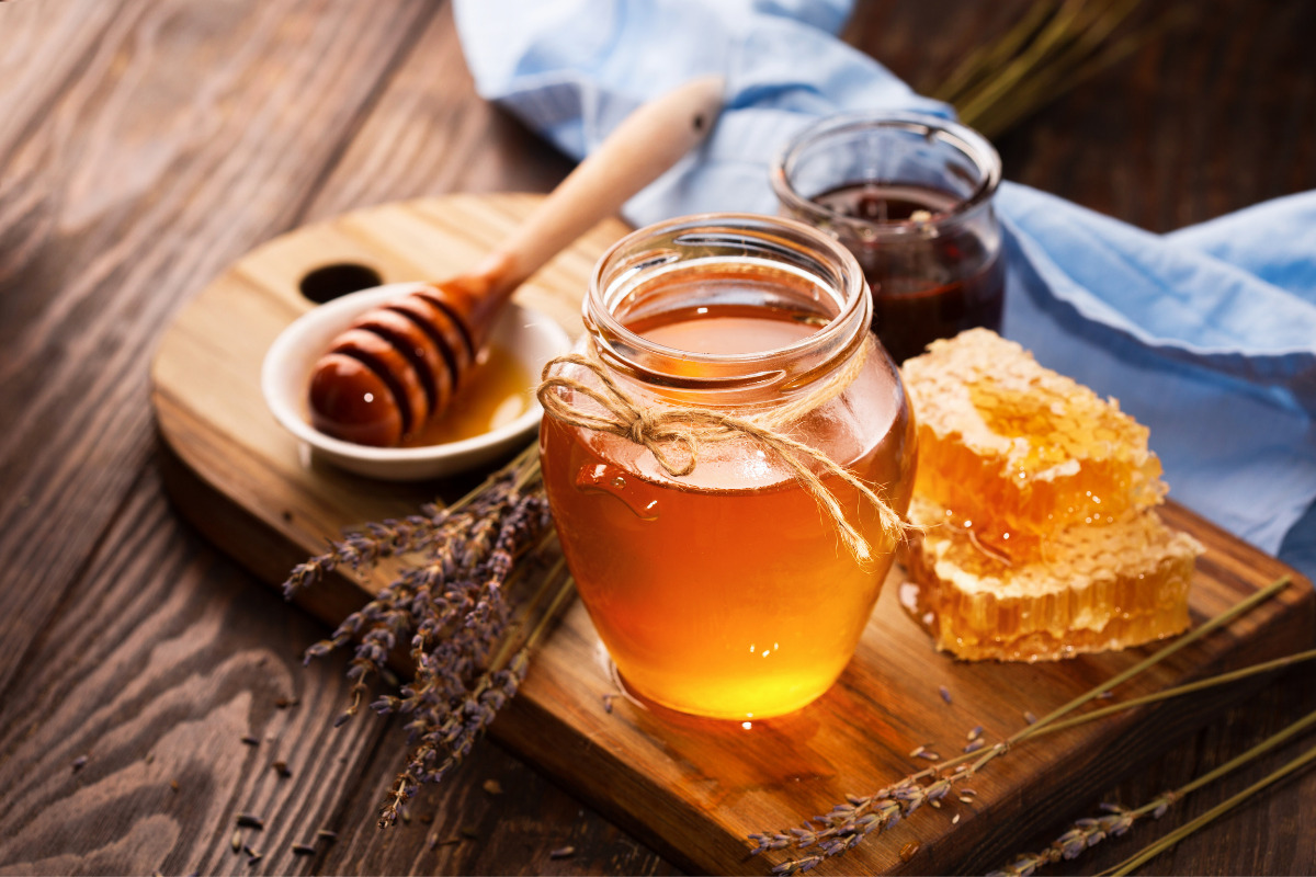 Honey in a jar and a honeycomb beside on a cutting board