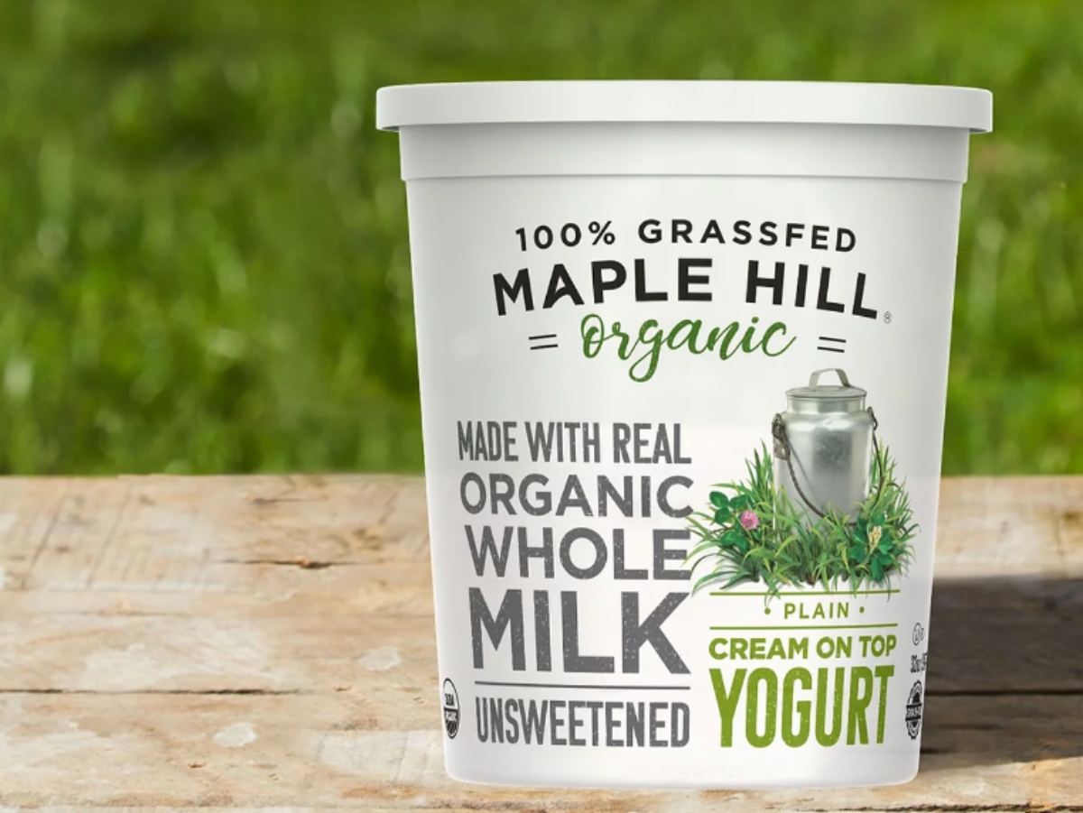 Maple hill organic yogurt on the wooden surface against the green background