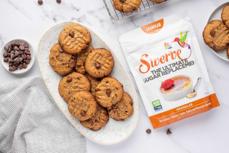 Low carb peanut butter cookies stacked on a oval white plate beside the package of sweetener
