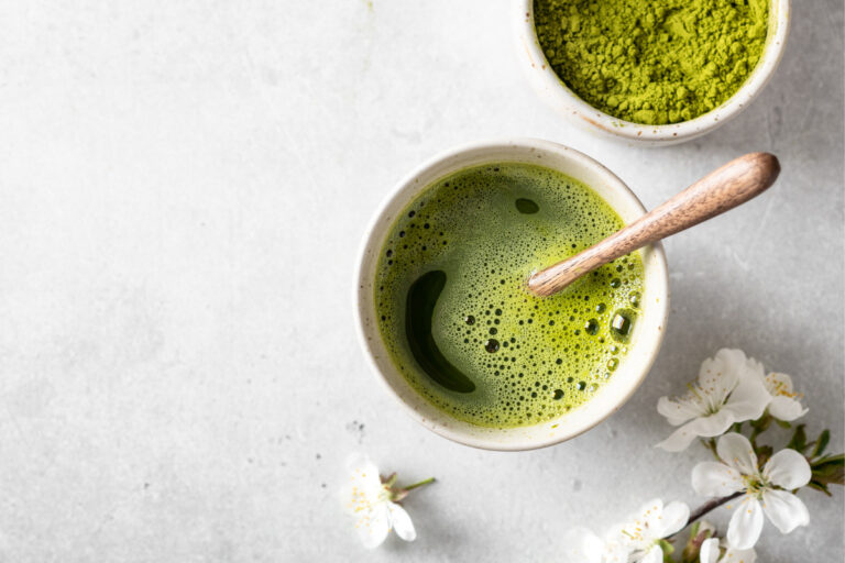 Matcha green tea in a cut with matcha powder in other cup beside