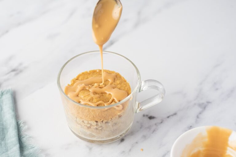 Low carb Blondie mug cake batter in a glass mug with a spoon above
