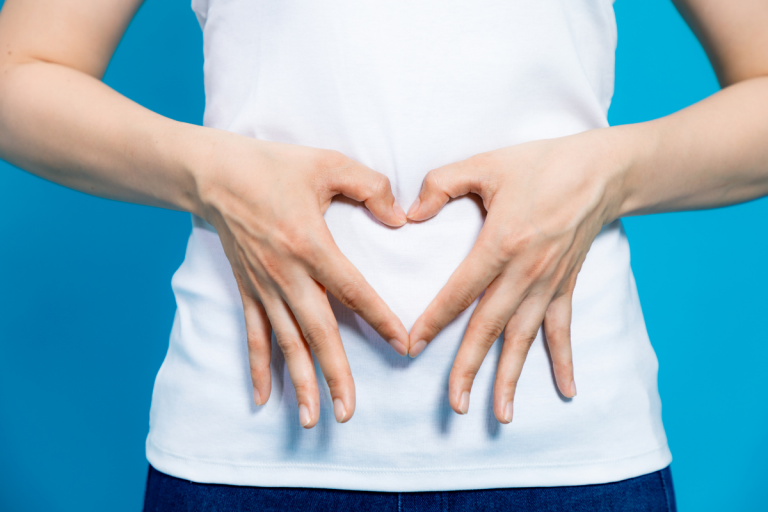 A woman forming a heart with her hand on her stomach