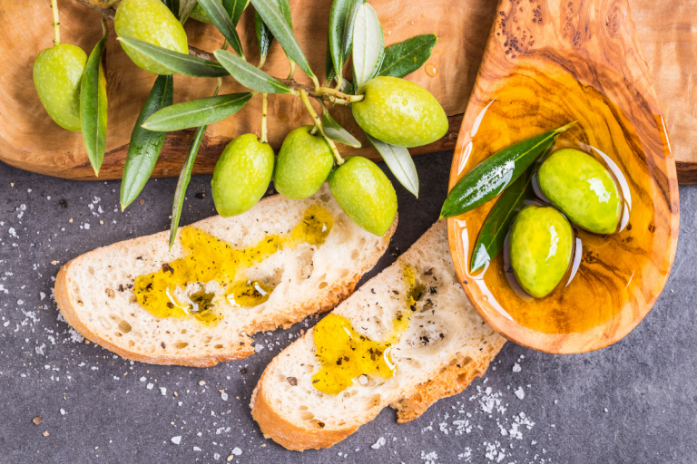 Olive oil drizzled on a slices of bread with olives beside