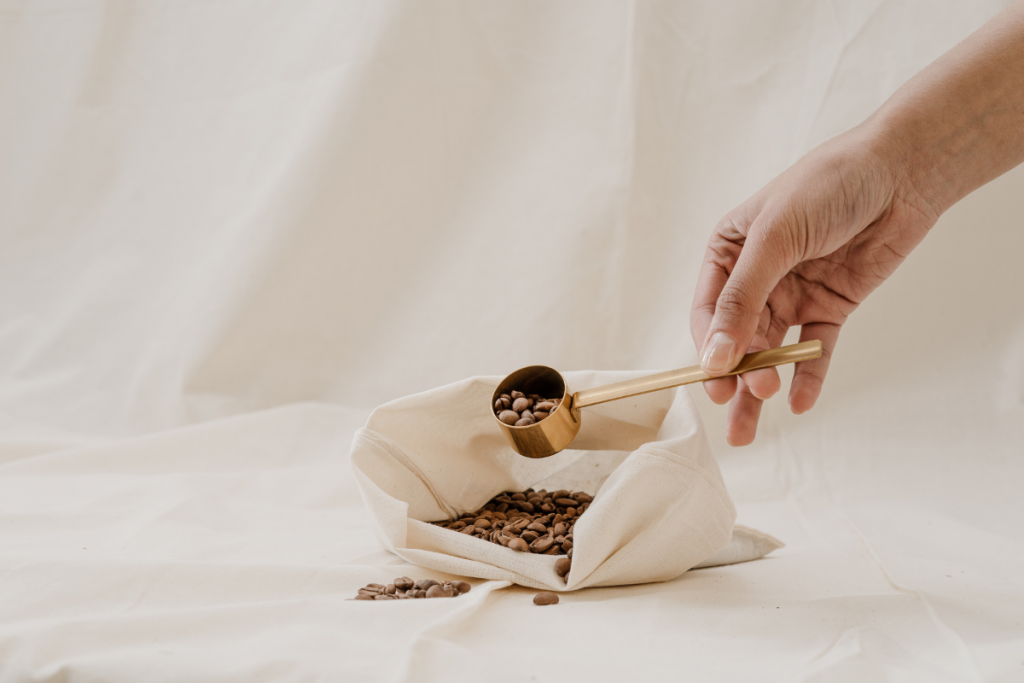 Person holding a golden scoop with coffee beans