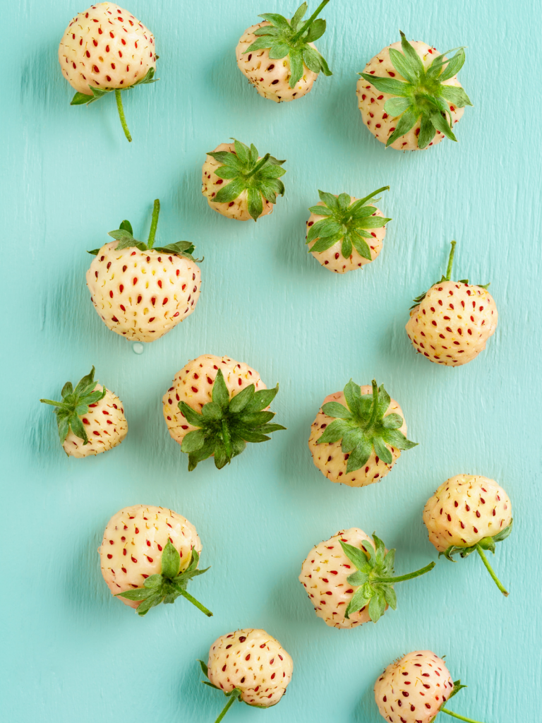 Pineberries scattered against the blue background