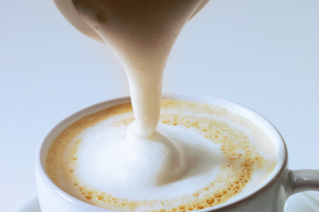 Pouring cream on cappuccino