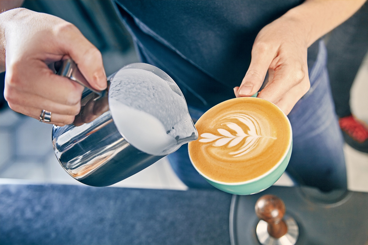 Person pouring milk into coffee