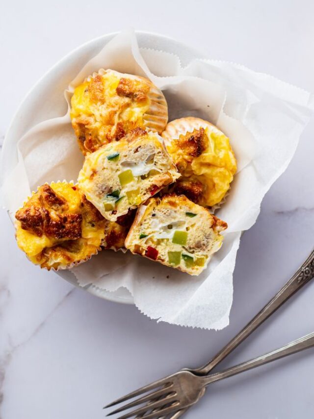 A basket of veggie egg muffins and a small bowl of veggies to the left and another veggie muffin off to the right