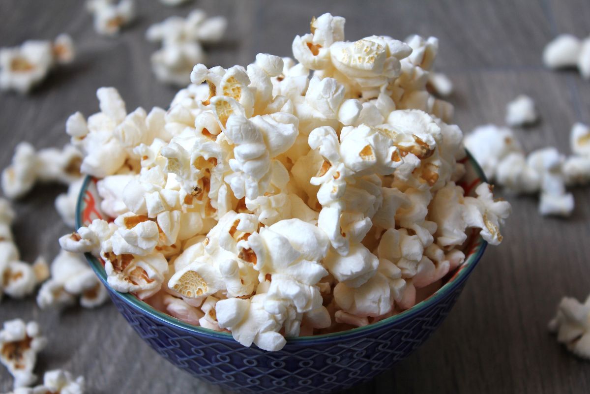 Popcorn in a blue bowl on top of a wooden table