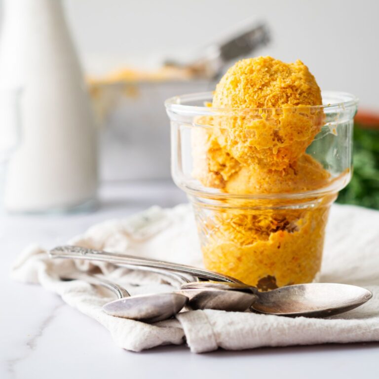 two scoops of carrot ice cream in a clear glass