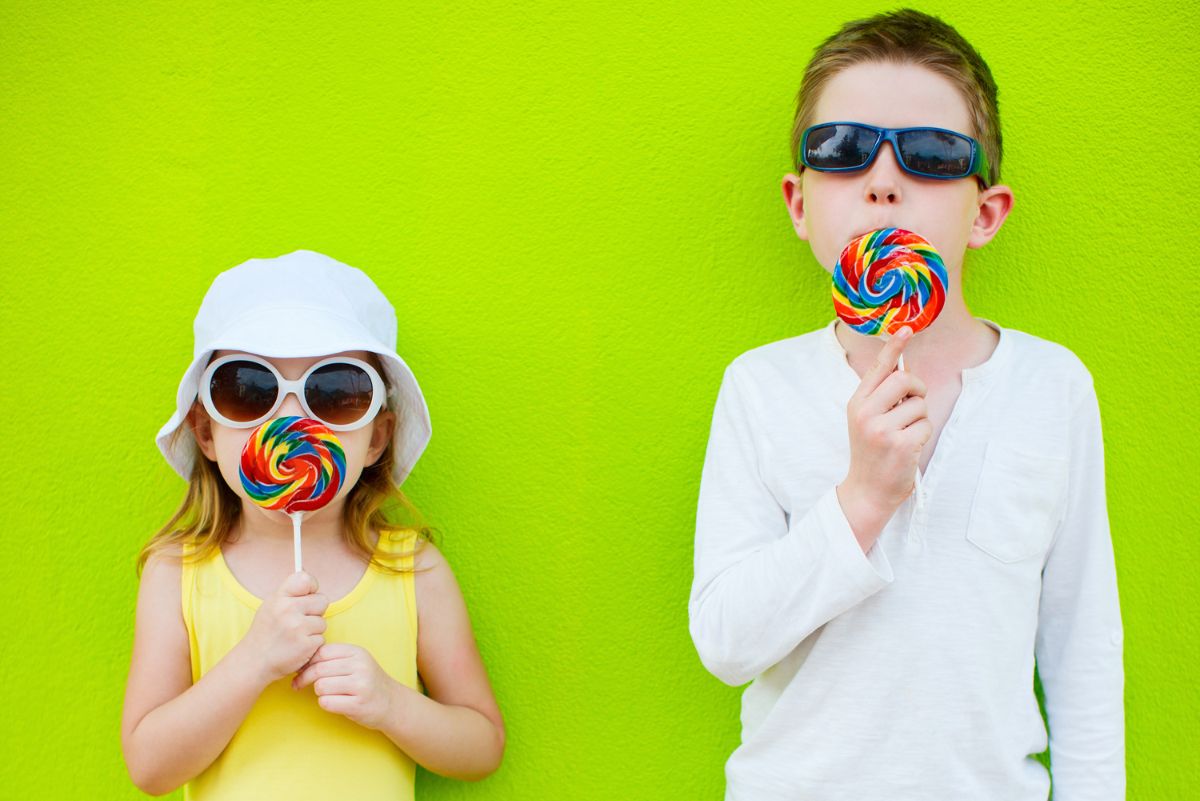 Two kids wearing sunglasses licking sugar free lollipops