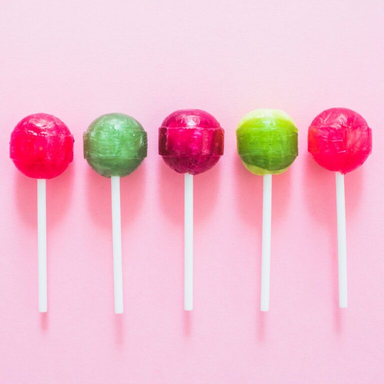 different colored lollipops lined along a pink background