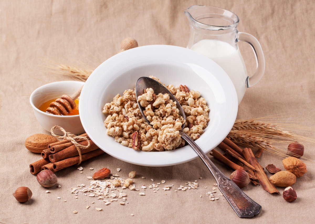 Plate of muesli with milk, honey, cinnamon and nuts over textile background