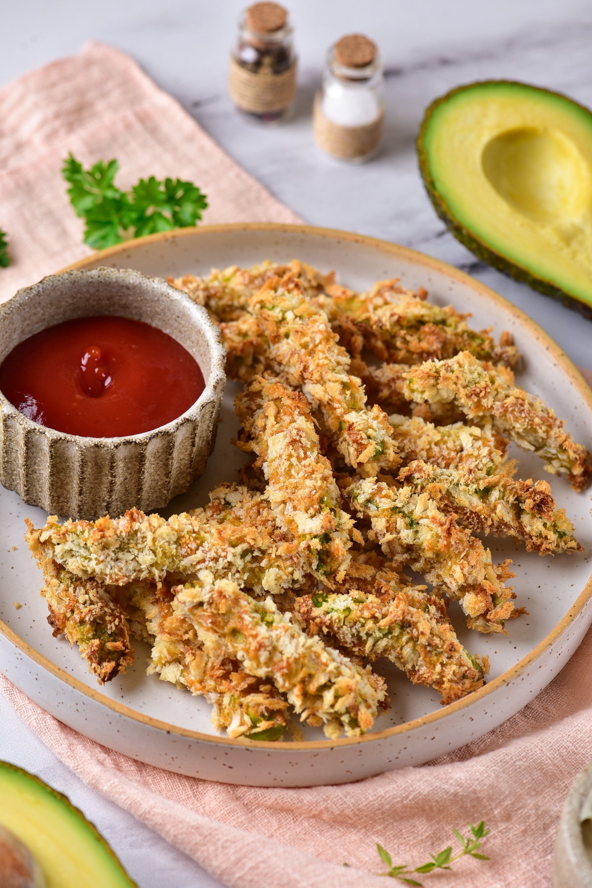 Avocado bites served on a plate with a cup of ketchup