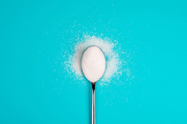 A spoon with sucralose against the blue background